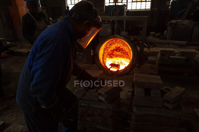 Trabajadores vertiendo metal fundido de frascos en moldes en fundición - foto de stock