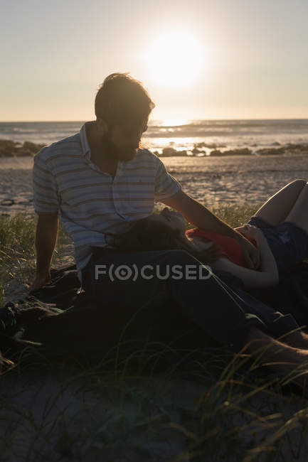 Jeune femme couchée sur les genoux mans à la plage — Photo de stock