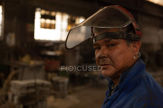Gros plan d'un travailleur regardant une caméra dans un atelier de fonderie — Photo de stock