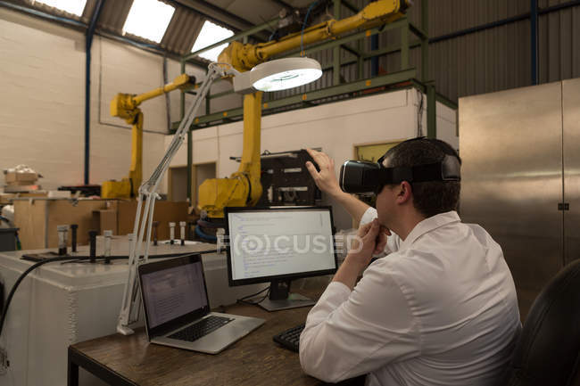Ingénieur en robotique utilisant un casque de réalité virtuelle au bureau dans un entrepôt — Photo de stock