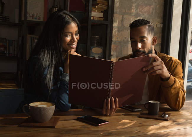 Heureux couple regardant le menu dans le café — Photo de stock