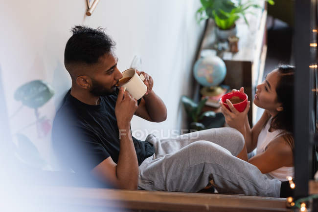 Side view of couple having coffee in stairs at home — Stock Photo