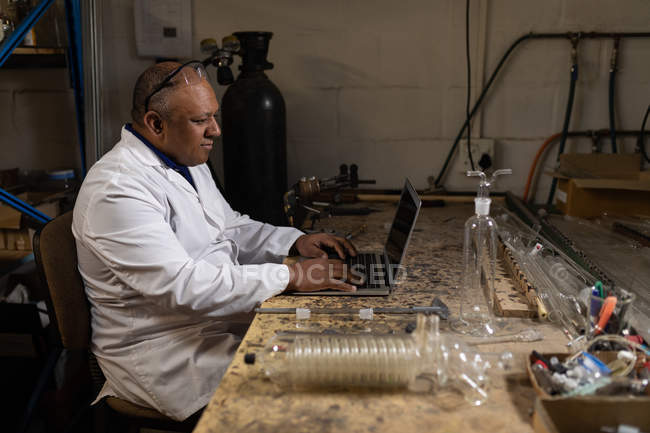 Side view of worker using laptop in glass factory — Stock Photo