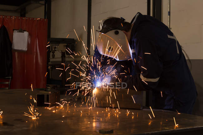 Robotic engineers using welding torch in warehouse — Stock Photo