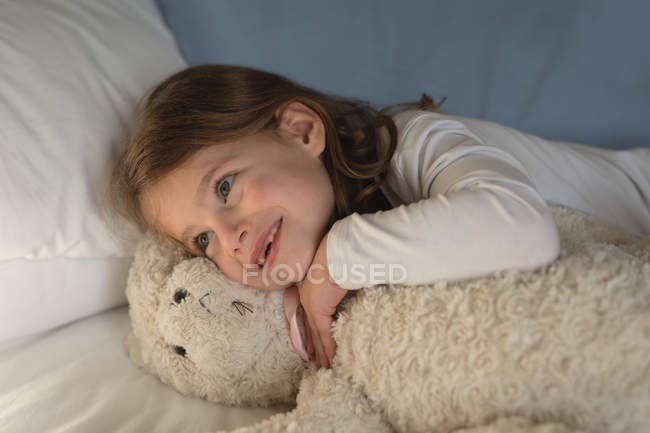 Menina relaxante com ursinho de pelúcia no quarto em casa — Fotografia de Stock