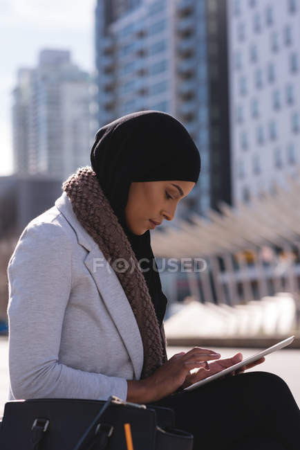 Vista lateral de la mujer hijab utilizando tableta digital en la ciudad - foto de stock