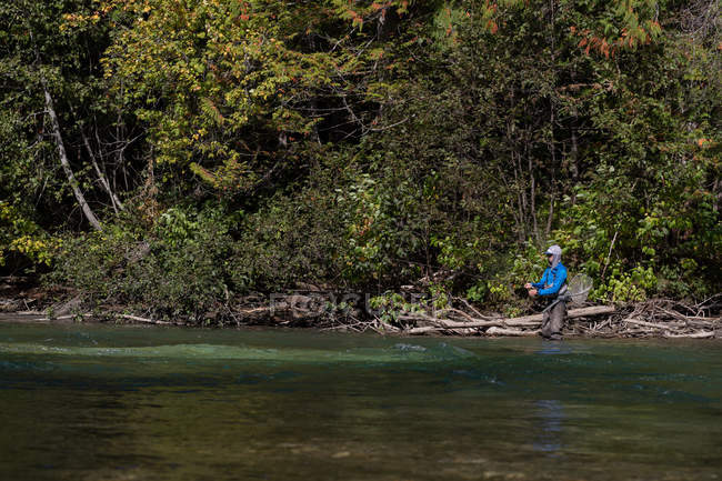 Рибалка літає на риболовлю в річці в сонячний день — стокове фото