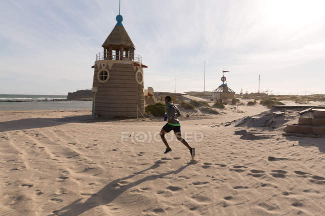 Мужчина бегает трусцой возле пляжа в солнечный день — стоковое фото