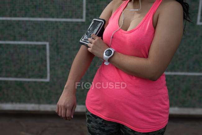Sección media del jogger femenino usando el teléfono móvil - foto de stock