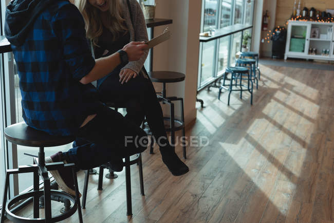 Ein Paar diskutiert auf einem Klemmbrett im Café — Stockfoto