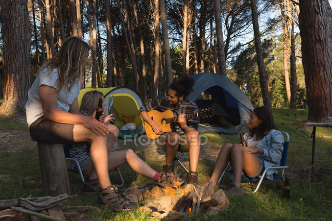 Grupo de amigos divirtiéndose cerca de la hoguera en el camping - foto de stock