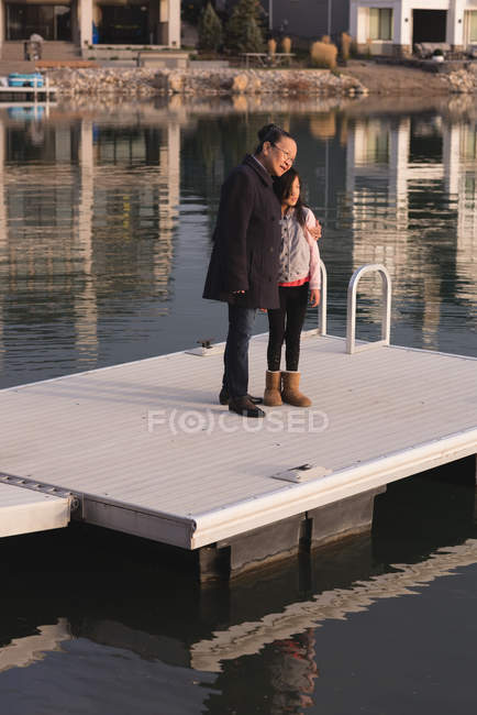 Side view of grandmother and granddaughter standing on pier near lake side — Stock Photo