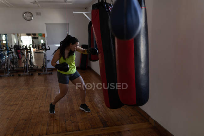 Jeune boxeuse pratiquant la boxe dans un studio de fitness — Photo de stock