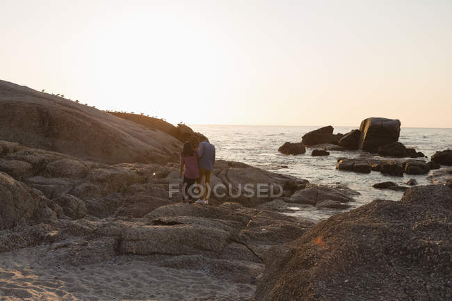 Rückansicht eines Paares, das in der Nähe des Meeres auf einem Felsen wandelt — Stockfoto