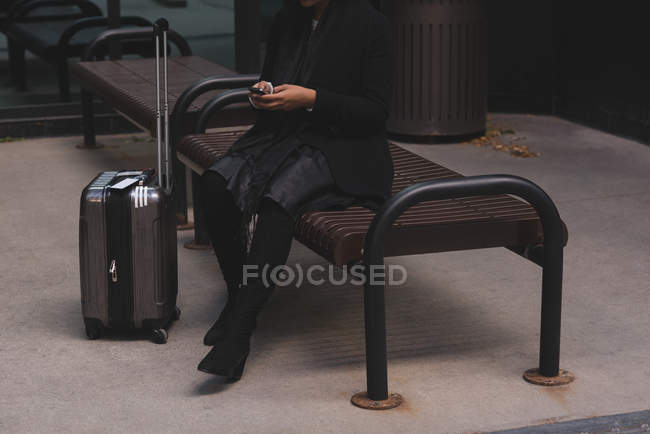 Низька частина жінки, що використовує мобільний телефон у місті — стокове фото