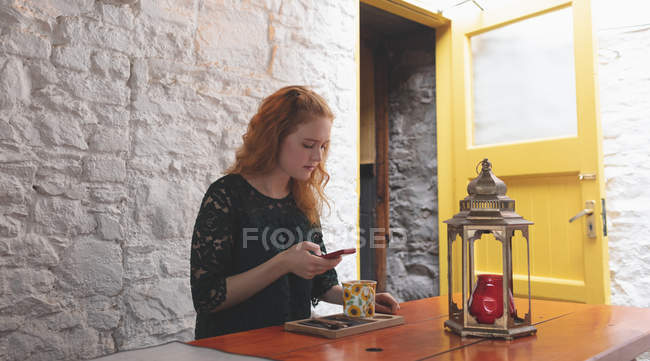 Pelirroja usando teléfono móvil en la cafetería - foto de stock