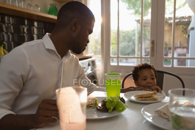 Отец кормит своего сына на кухне дома. — стоковое фото