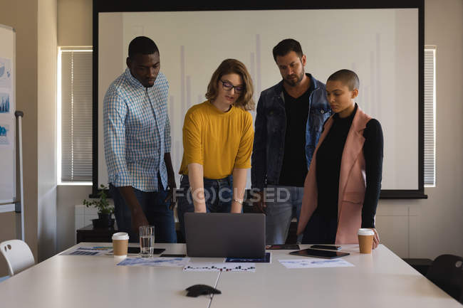Виконавці обговорюють ноутбук у конференц-залі в офісі — стокове фото