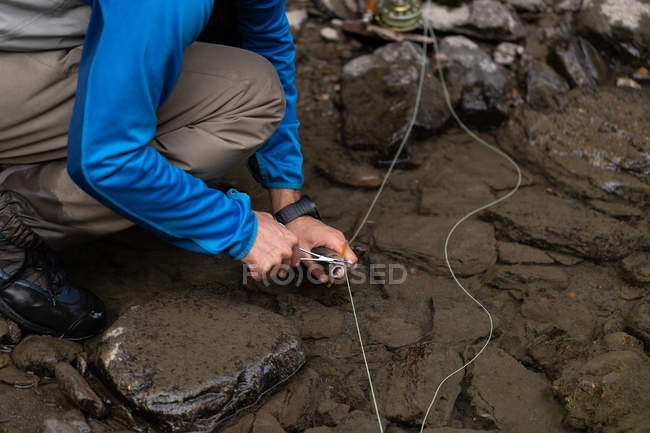 Niedriger Abschnitt des Fischers entfernt Angelhaken vom Fisch mit der Schere — Stockfoto