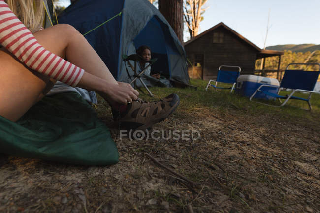 Primo piano della donna che indossa le scarpe al campeggio — Foto stock
