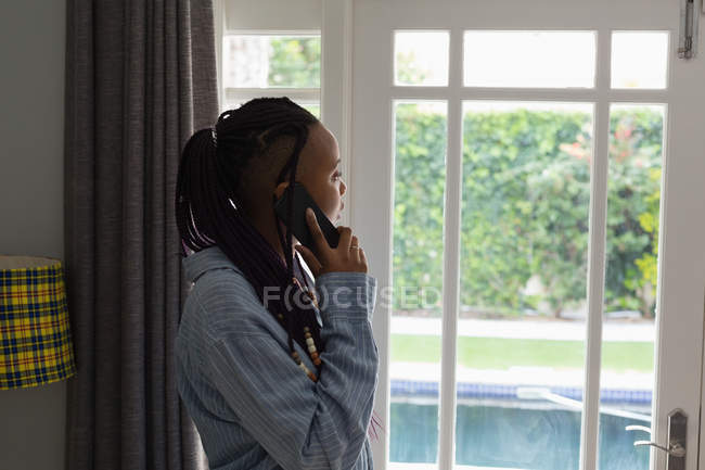 Femme parlant au téléphone dans un salon à la maison — Photo de stock