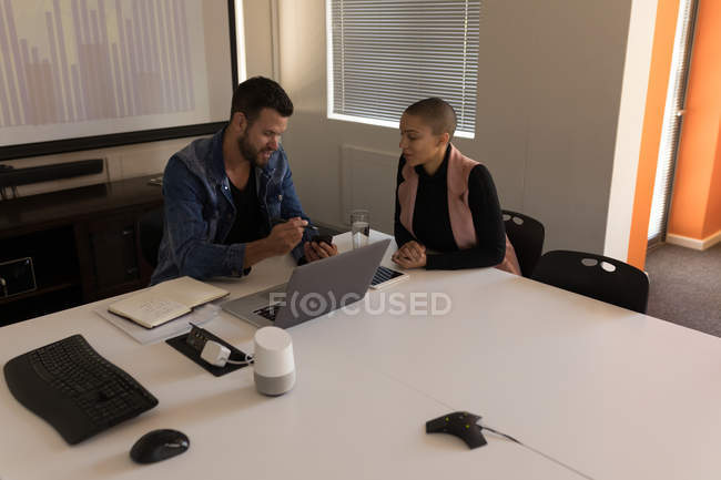 Dirigenti che discutono sul cellulare in sala conferenze in ufficio — Foto stock