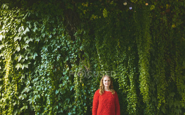 Redhead woman standing against plant creeper in outdoor cafe — Stock Photo