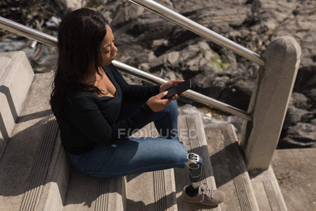 Высокий угол обзора женщины-инвалида с помощью мобильного телефона на лестнице — стоковое фото