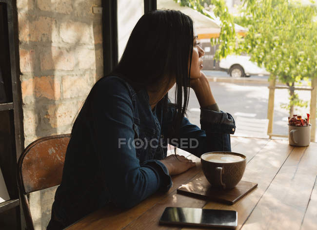 Вид збоку жінки, що дивиться через вікно в кафе — стокове фото