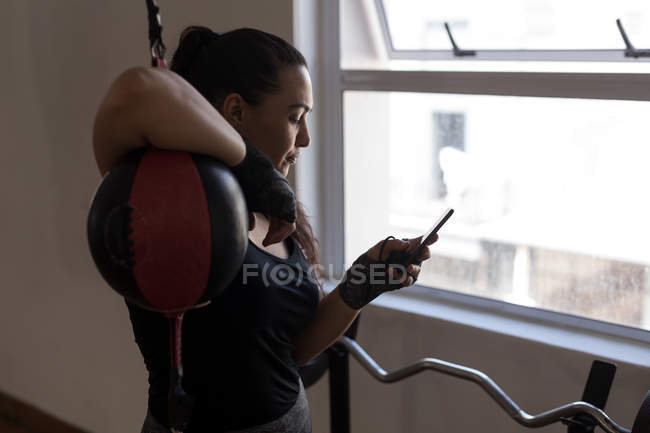 Молодая боксерша с мобильным телефоном в фитнес-студии — стоковое фото