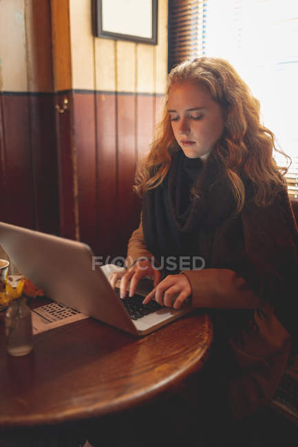 Donna rossa che utilizza il computer portatile in caffè — Foto stock