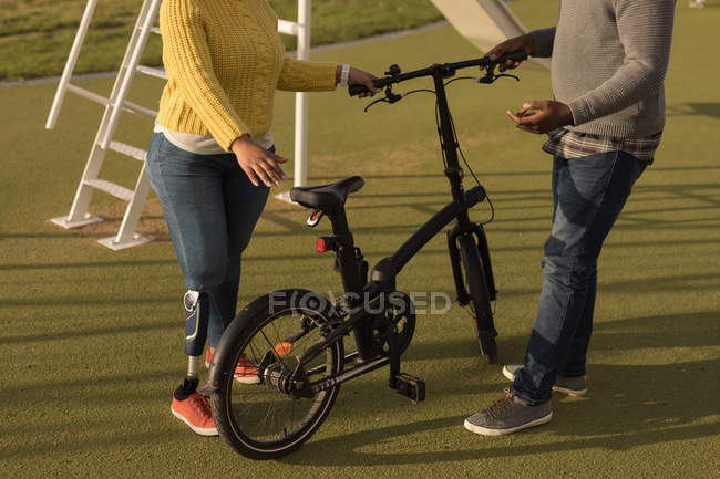 Low section of couple holding bicycle in the garden — Stock Photo