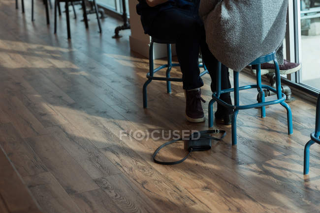 Section basse du couple assis dans un café avec sac à main tombé — Photo de stock
