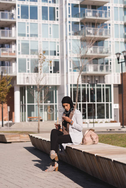 Hijab mulher usando telefone celular enquanto toma café na cidade — Fotografia de Stock