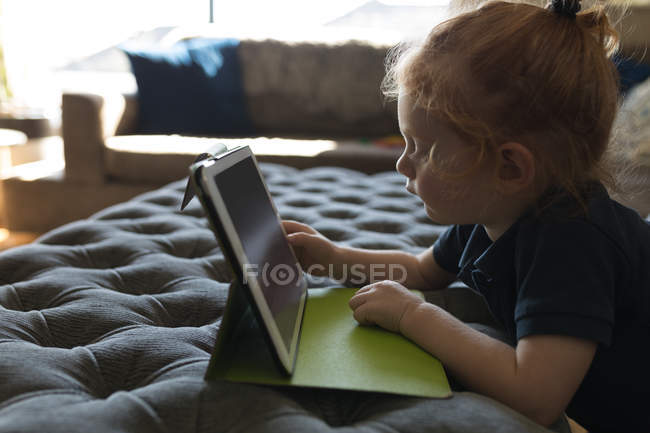 Vista lateral da menina usando tablet digital na sala de estar em casa — Fotografia de Stock