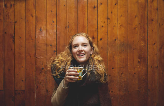 Рыжая женщина держит кофейную кружку в кафе — стоковое фото