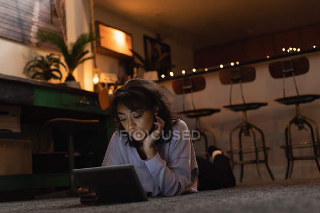 Beautiful woman using digital tablet on floor at home — Stock Photo