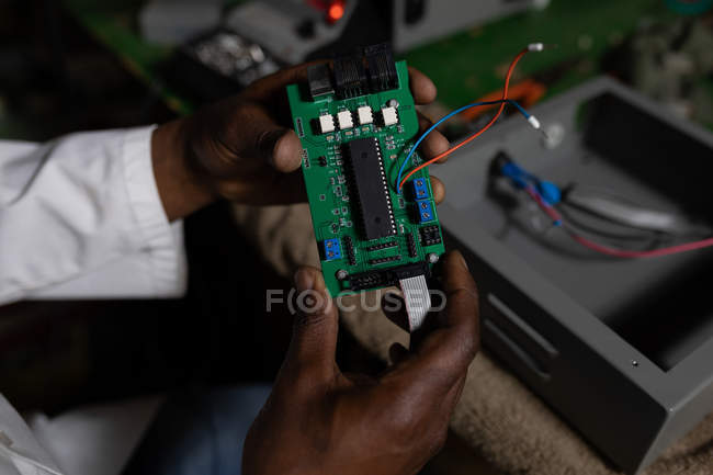 Gros plan du travailleur examinant une carte de circuit imprimé dans une usine de verre — Photo de stock