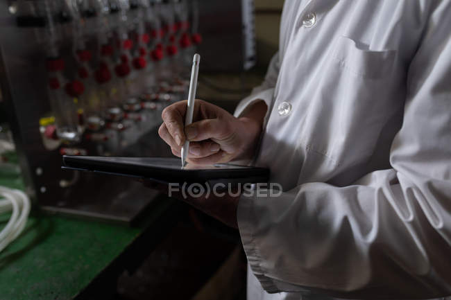 Sección media del trabajador que usa tableta digital en fábrica de vidrio - foto de stock