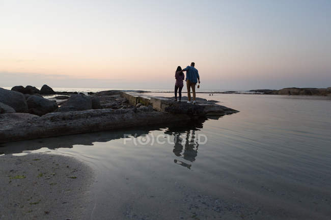 Vista trasera de pareja de pie cerca del lado del mar - foto de stock