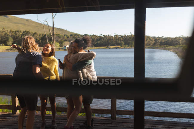 Des amis s'embrassent dans une cabane près du lac — Photo de stock