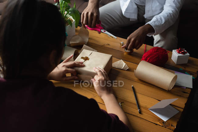Couple wrapping gift box in living room at home — Stock Photo