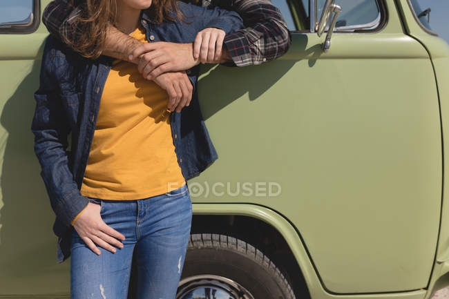 Sección media del hombre abrazando a la mujer a través de la ventana del coche - foto de stock
