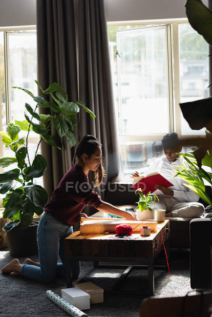Жінка обгортає подарункову коробку у вітальні вдома — стокове фото