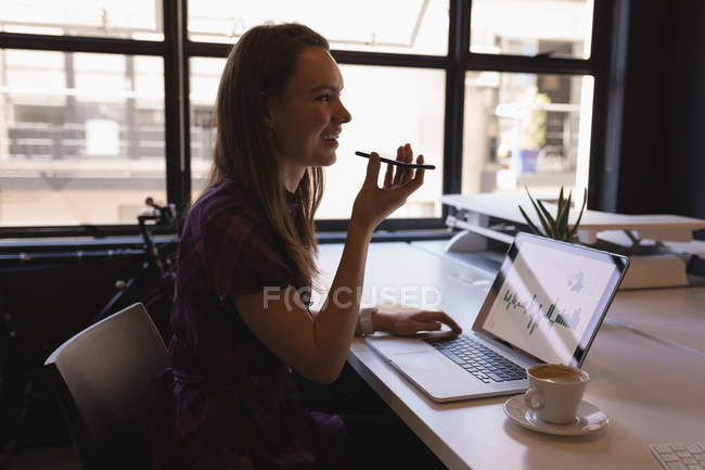 Деловая женщина разговаривает по мобильному телефону за столом в офисе — стоковое фото