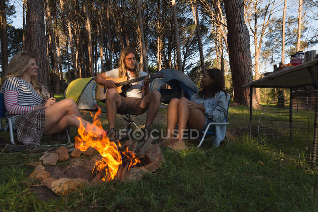 Grupo de amigos se divertindo perto de fogueira no acampamento — Fotografia de Stock