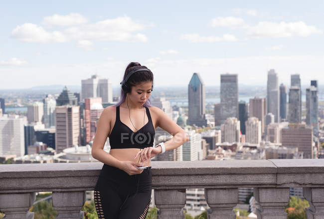 Жінка-бігун дивиться на смарт-годинник у сонячний день — стокове фото