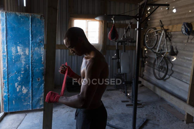 Male boxer tying hand wrap on hand in boxing club — Stock Photo