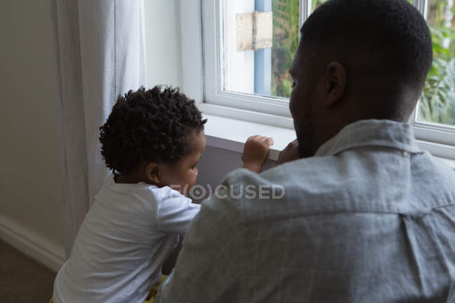 Pai e filho sentados perto da janela em casa — Fotografia de Stock