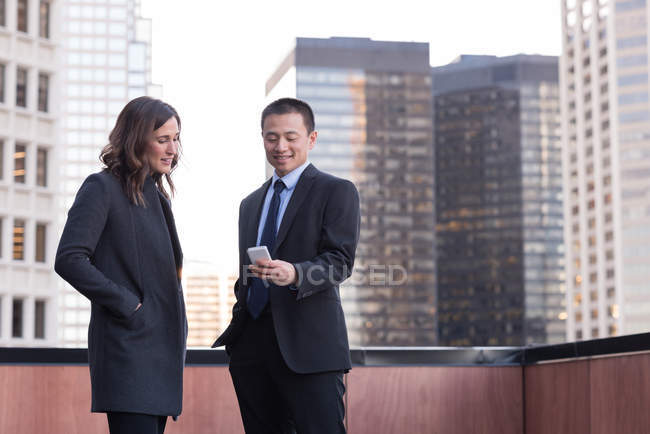 Geschäftsleute diskutieren auf Balkon im Hotel am Handy — Stockfoto
